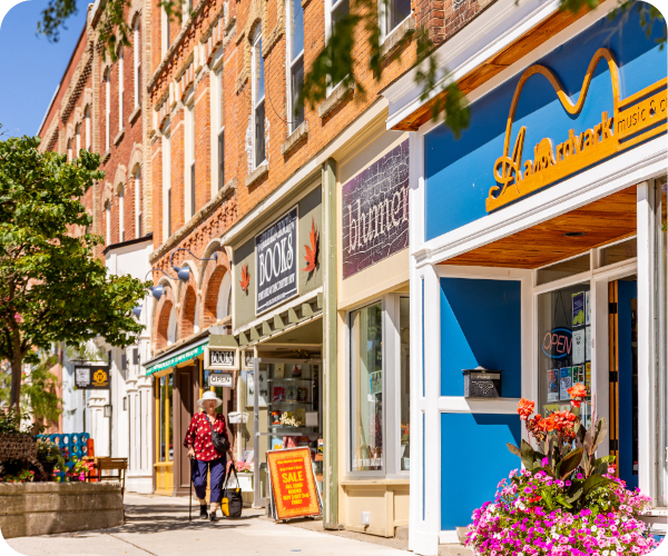 A historic streetscape with shops lining the sidewalk and trees.