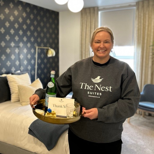 The Nest Suites a women in a rental suite holding a tray of goodies