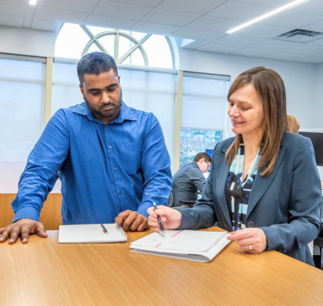 A man and a woman are reviewing a document on a table.