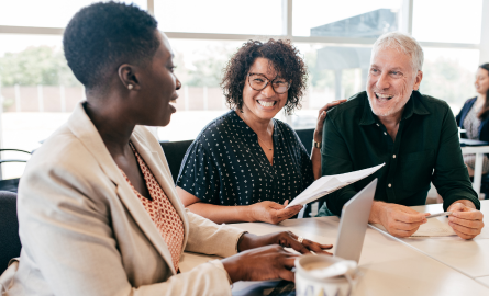 Three people are sitting at a table and smiling.