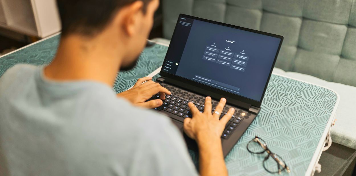 A person typing on a laptop sitting on a table