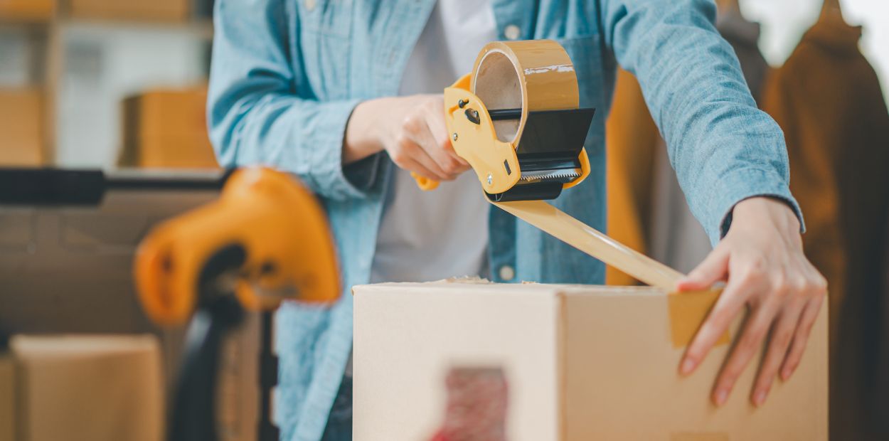 A person taping shut a cardboard box