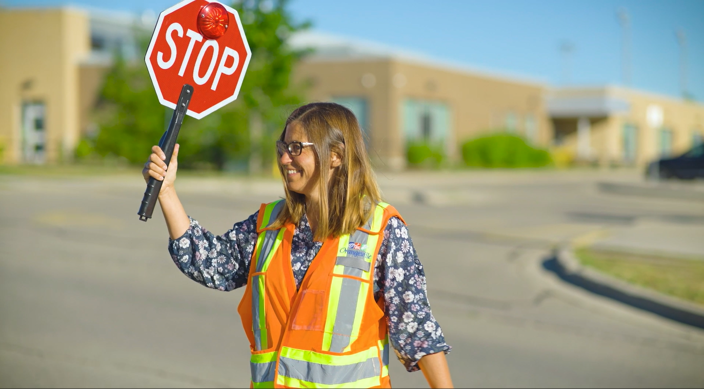 A crossing guard holds up a stop sign for pedestrians to cross the street