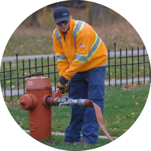 A person uses tools to turn on a fire hydrant attached to a hose