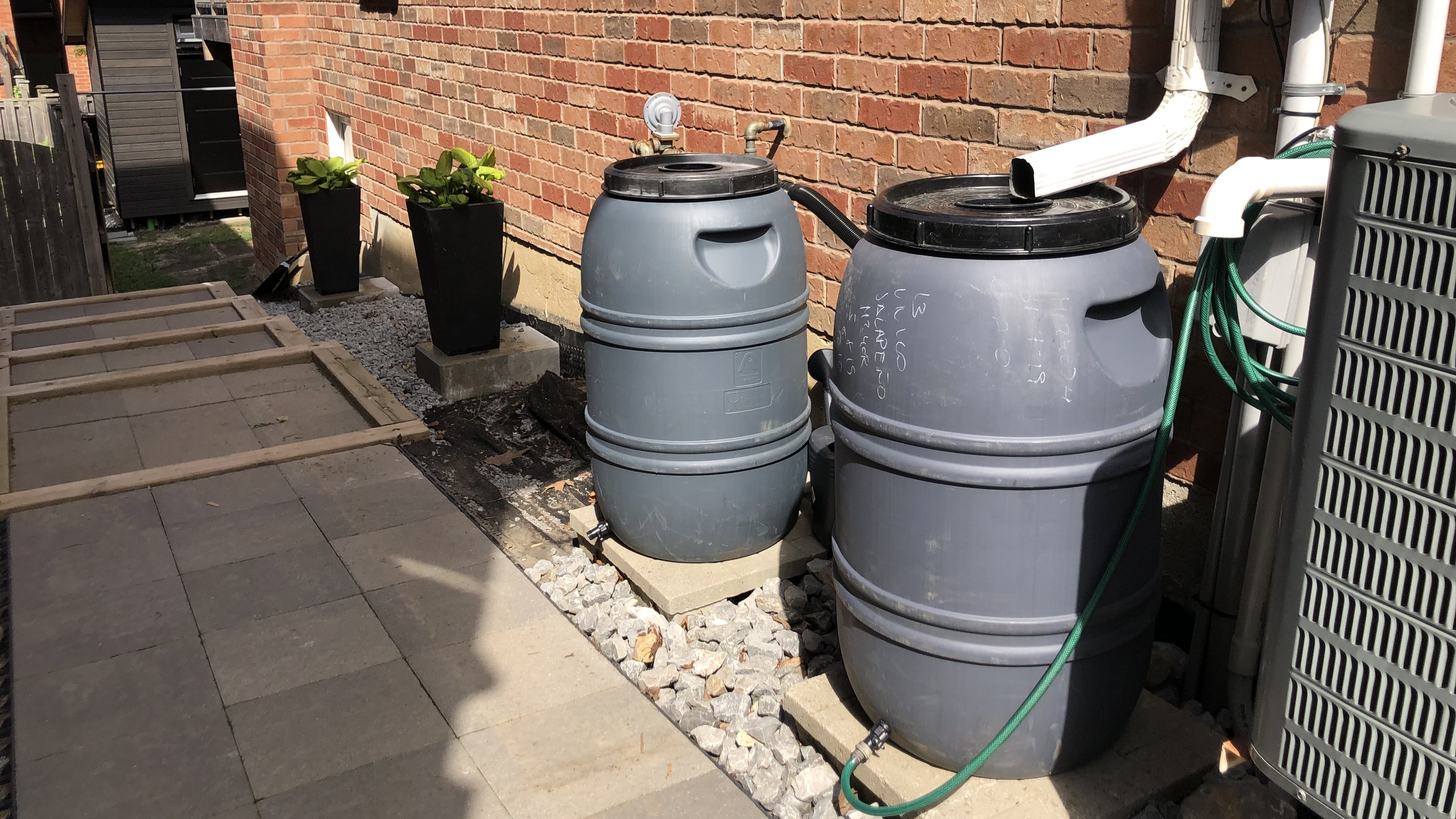 Row of rain barrel lined up against a brick wall