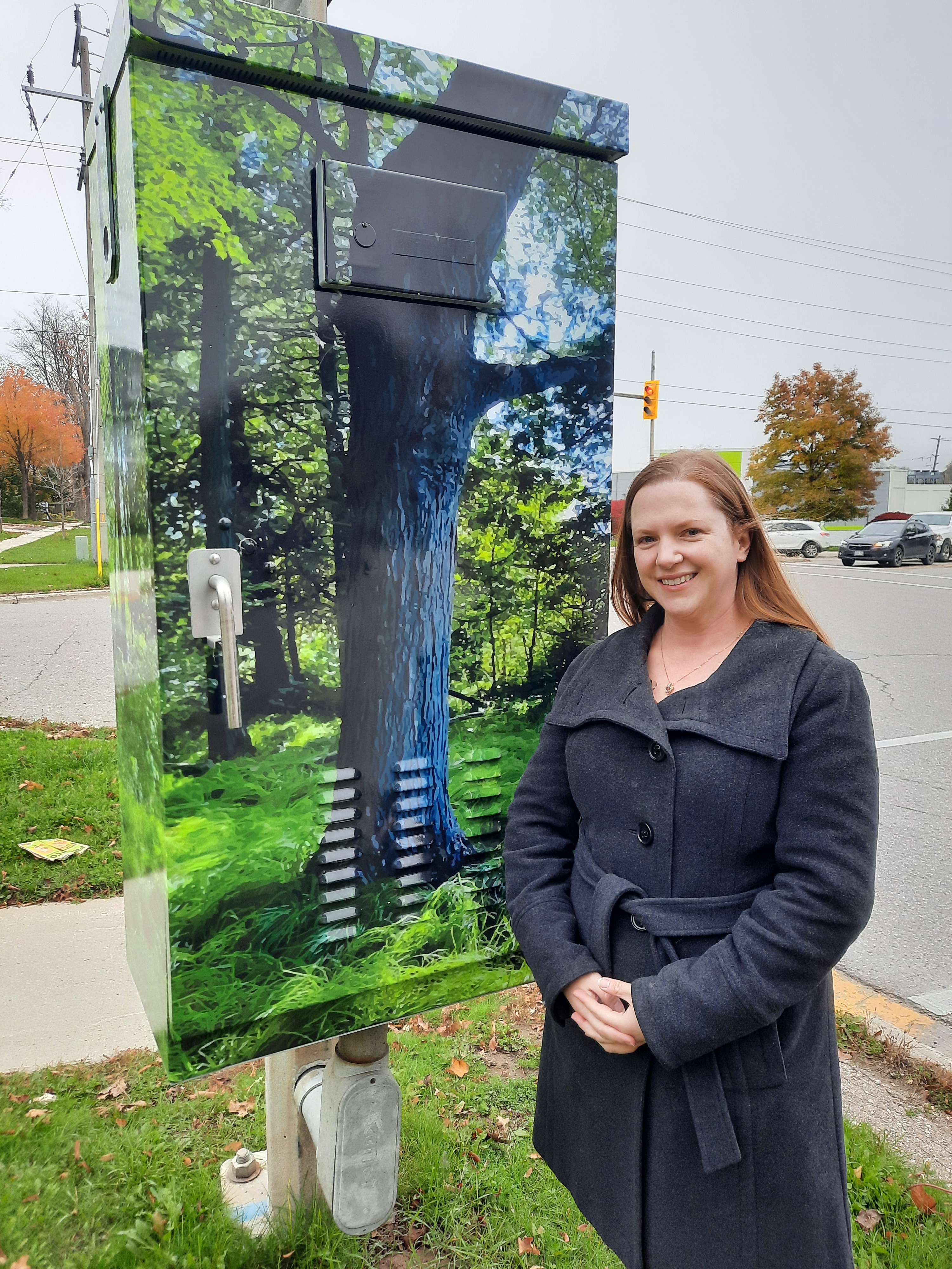 Artist standing next to utility box with art installation