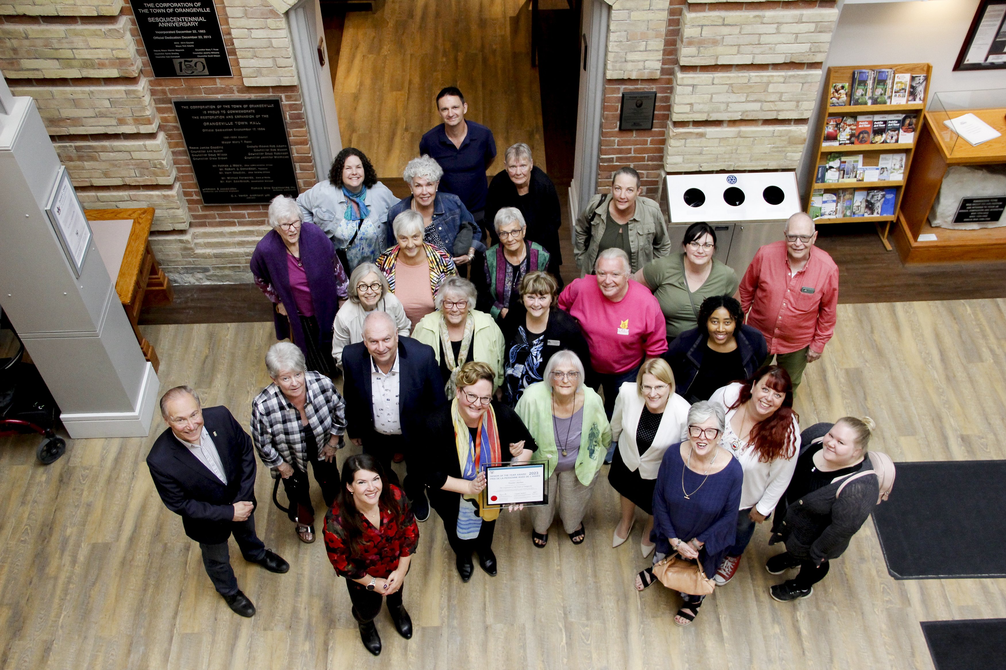 Council and supports gather in Orangeville Town Hall atrium looking up at the camera in celebration of Heather Sheehan.