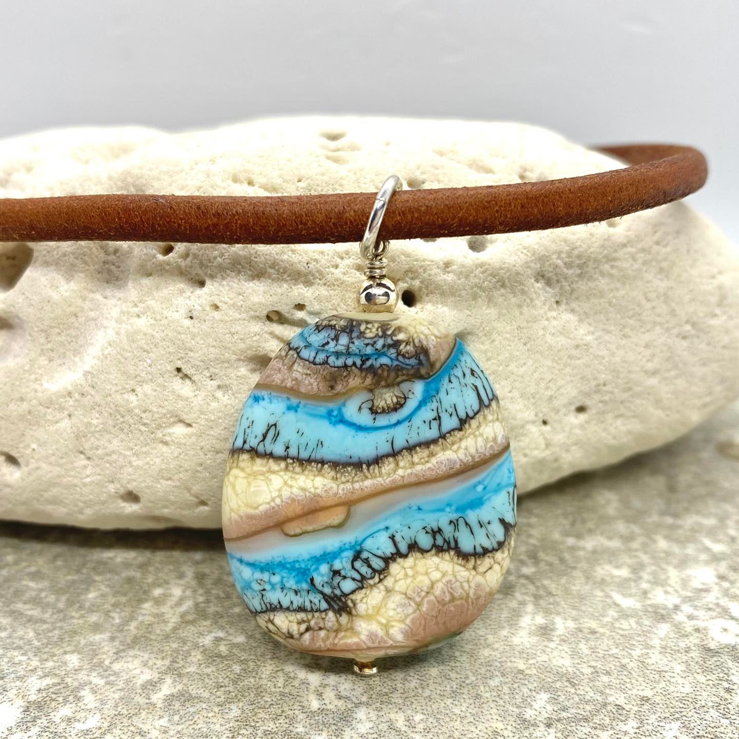 A blue and gold pendant necklace on a leather chain