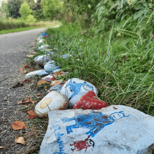 Colourful painted rocks alongside a trail placed to resemble a snake