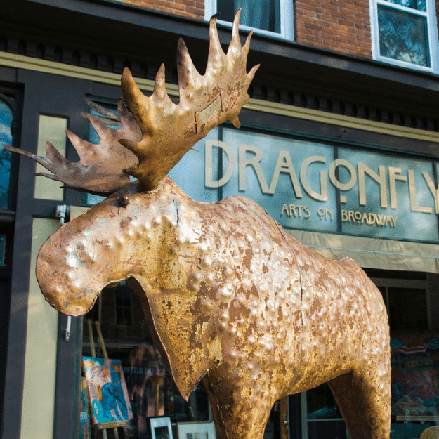 Statue of a moose sculpture standing in front of a store on Broadway