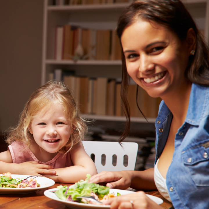 Young woman and child sitting at table eating dinner