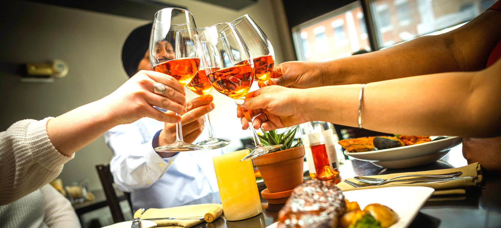 A group of people are clinking wine glasses together over a meal.