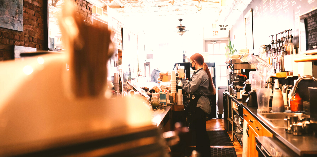 Barista preparing drink behind cafe counter