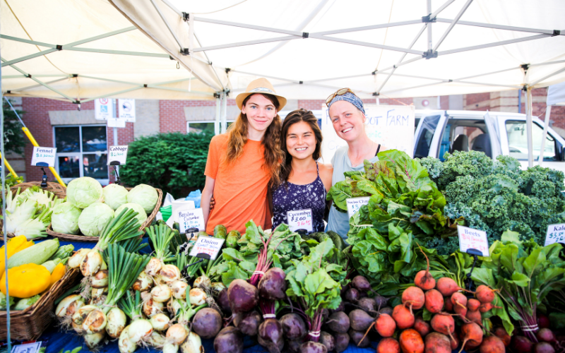 Three people standing behind a table of fresh produce