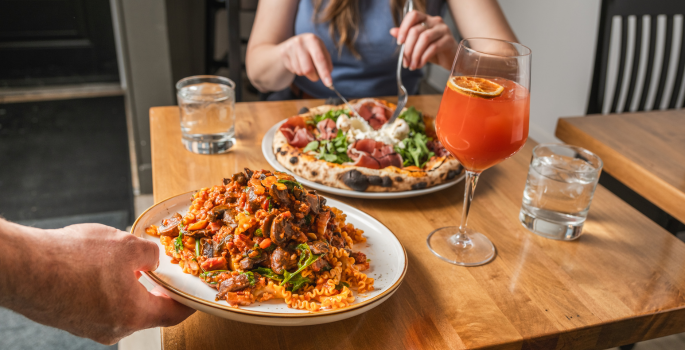 A person is dining on a piza and pasta at a restaurant