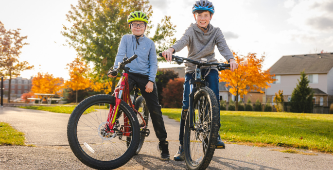 Two boys on bikes rest in a park