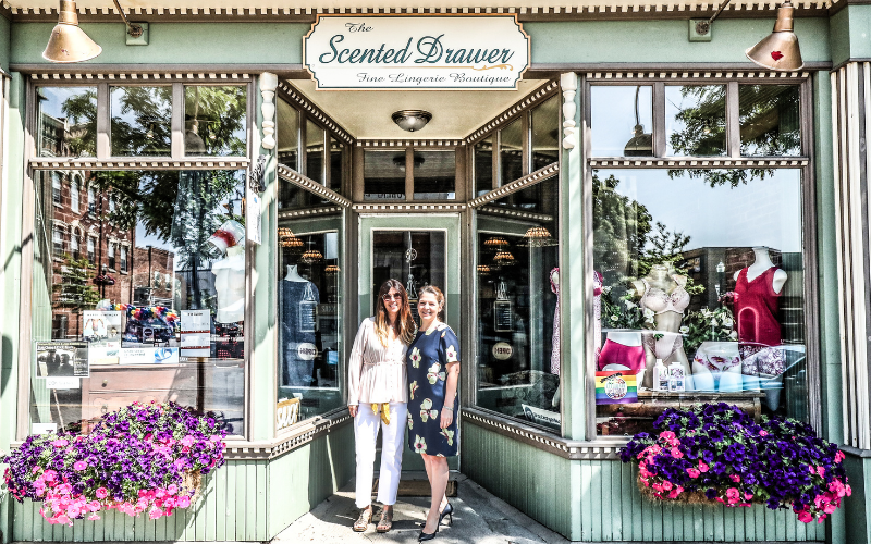 Two woman standing in front of a downtown shop