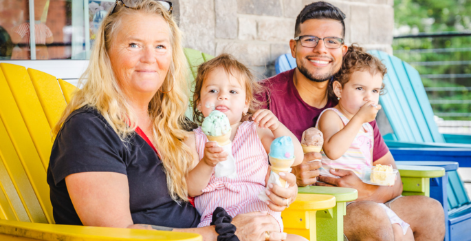 A family of four smile while sitting on the ice and ice fishing
